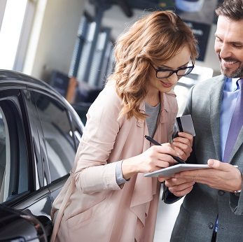 Woman signing car agreement in the showroom